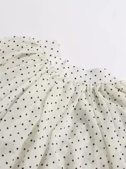 Blouse blanche pour femme col en V manches longues lacées et à volants.