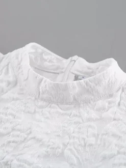 Blouse texturée en jacquard à manches bouffantes col montant taille péplum ourlet évasé