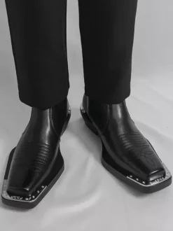 Bottines noires à bout carré et talon épais ornées de détails métalliques