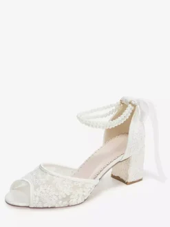 Chaussures de mariée en dentelle à bout ouvert ornées de fleurs de perles et de talons épais.