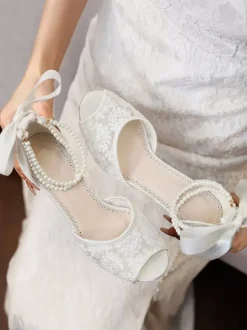 Chaussures de mariée en dentelle à bout ouvert ornées de fleurs de perles et de talons épais.