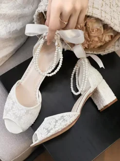 Chaussures de mariée en dentelle à bout ouvert ornées de fleurs de perles et de talons épais.