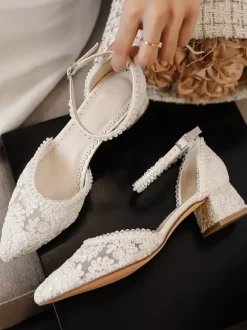 Chaussures de mariée ivoire à bout pointu talon compensé et bride cheville ornées de dentelle.
