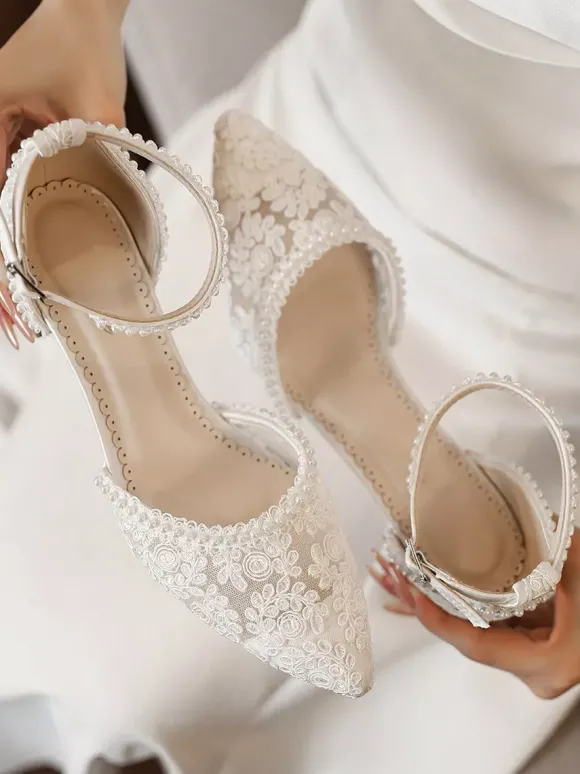 Chaussures de mariée ivoire à bout pointu talon compensé et bride cheville ornées de dentelle.