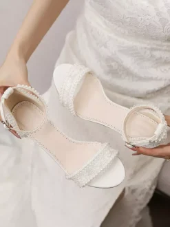Chaussures de mariée ivoire à bout ouvert et talon compensé ornées de dentelle.