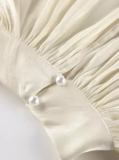 Chemisier oversize en satin crème brillant à col montant froncé manches ballon et poignets perlés