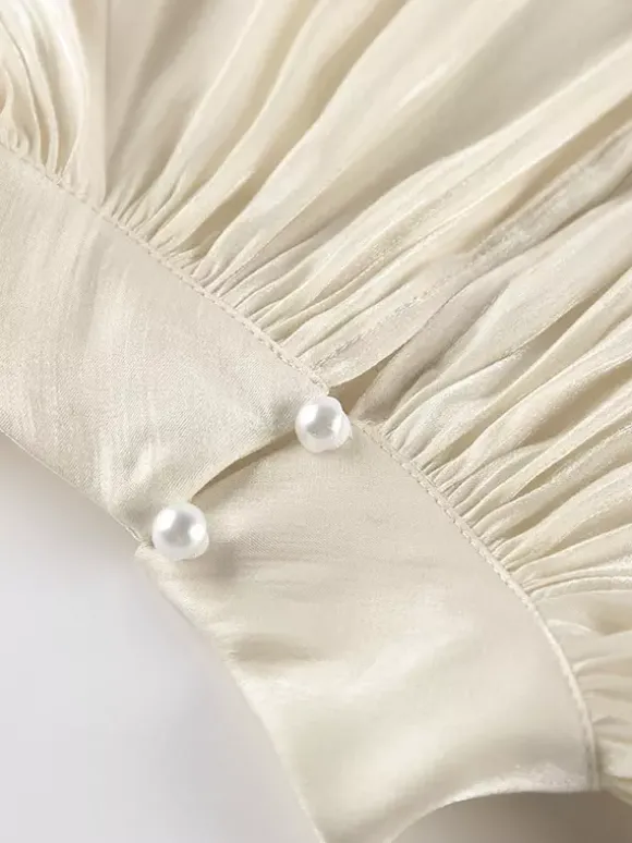 Chemisier oversize en satin crème brillant à col montant froncé manches ballon et poignets perlés