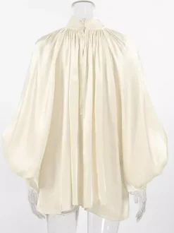 Chemisier oversize en satin crème brillant à col montant froncé manches ballon et poignets perlés