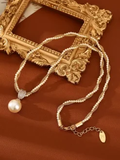Collier élégant de perles à plusieurs rangs serti de strass carré et orné d'une perle en forme de larme. Breloque en perle.