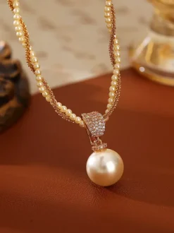 Collier élégant de perles à plusieurs rangs serti de strass carré et orné d'une perle en forme de larme. Breloque en perle.