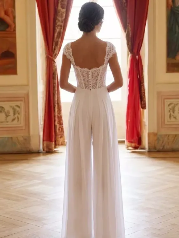 Combinaison de mariée en dentelle appliquée longue jusqu'au sol décolleté travaillé manches courtes taille naturelle couleur ivoire