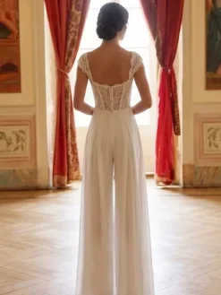 Combinaison de mariée en dentelle appliquée longue jusqu'au sol décolleté travaillé manches courtes taille naturelle couleur ivoire