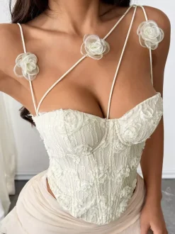 Corsets blancs sexy sans manches à bretelles et décolleté ajusté ornés de fleurs.