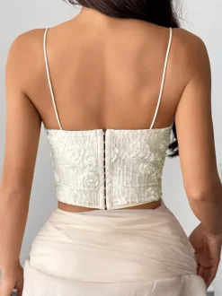 Corsets blancs sexy sans manches à bretelles et décolleté ajusté ornés de fleurs.