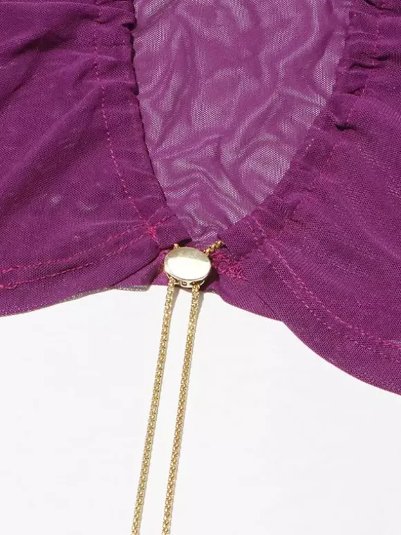Crop top violet à col montant et manches longues à découpes apparentes.