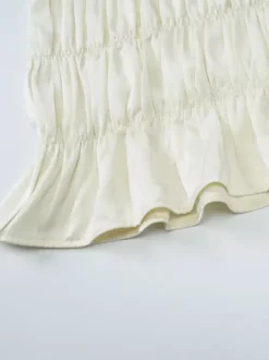 Ensemble deux pièces abricot chic plissé idéal pour les vacances avec bretelles et col à volants jupe sans manches à volants.
