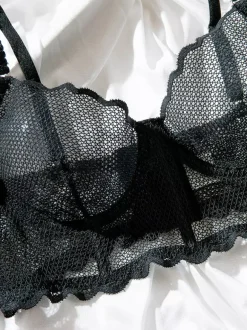 Ensemble soutien-gorge et culotte deux pièces noirs à volants en résille orné de motifs.