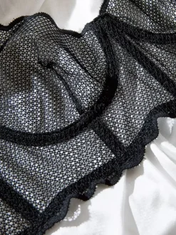 Ensemble soutien-gorge et culotte deux pièces noirs à volants en résille orné de motifs.