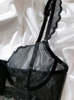 Ensemble soutien-gorge et culotte deux pièces noirs à volants en résille orné de motifs.