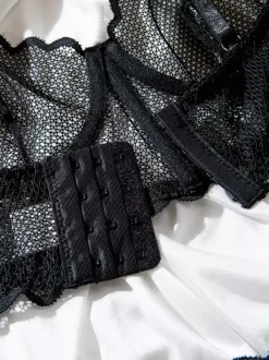 Ensemble soutien-gorge et culotte deux pièces noirs à volants en résille orné de motifs.