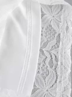 Ensemble deux pièces en dentelle florale blanche : haut court à fines bretelles et pantalon large transparent.