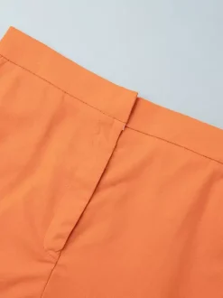 Ensemble deux pièces jupe et haut orange à boutons rétro style resort en lin col V sans manches.