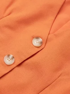 Ensemble deux pièces jupe et haut orange à boutons rétro style resort en lin col V sans manches.