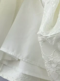 Robe blanche chic à n艙uds sculptants et sans manches col carré idéale pour une soirée romantique.