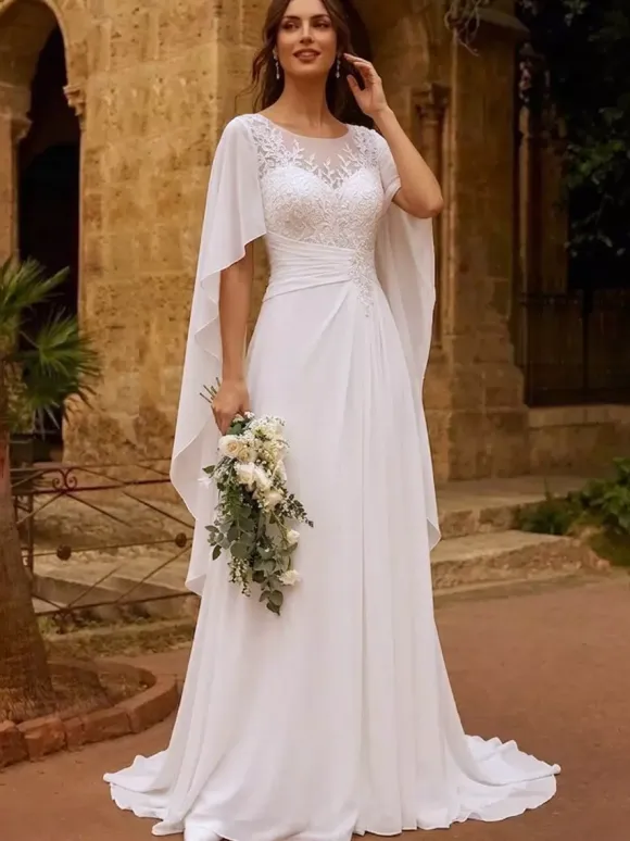 Robe de mariée bohème en dentelle col bijou manches longues et traîne en mousseline de soie.