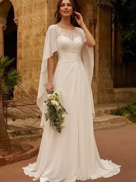 Robe de mariée bohème en dentelle col bijou manches longues et traîne en mousseline de soie.