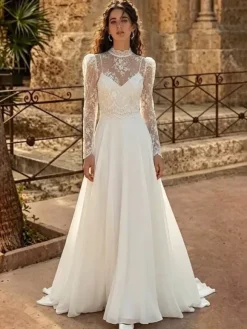 Robe de mariée deux pièces en dentelle et mousseline col rond coupe trapèze avec traîne boutons et manches longues.