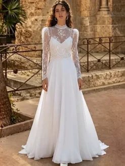 Robe de mariée deux pièces en dentelle et mousseline col rond coupe trapèze avec traîne boutons et manches longues.