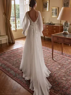 Robe de mariée bohème en mousseline et dentelle coupe trapèze avec traîne taille naturelle fermeture éclair manches longues col en V blanche
