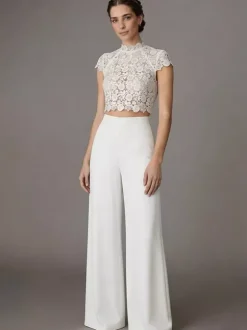 Robe de mariée deux pièces en crêpe stretch décolleté travaillé longueur au sol fermeture éclair manches courtes.