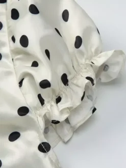 Robe longue crème flatteuse à col en V et pois noirs idéale pour les soirées.